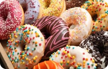 Nahaufnahme von mehreren mit Zuckerguss und bunten Streuseln verzierten Donuts