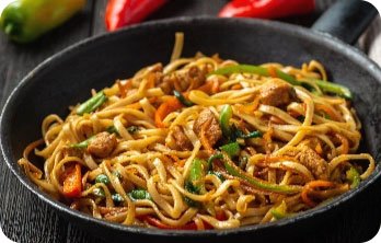 Pfanne mit gebratenen Nudeln, Gemüse und Fleischstücken