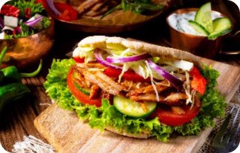 Döner-Sandwich mit Salat, Tomaten, Gurken und Zwiebeln auf Holzbrett