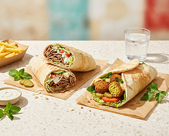 Döner-Sandwich mit Salat, Tomaten, Gurken und Zwiebeln auf Holzbrett